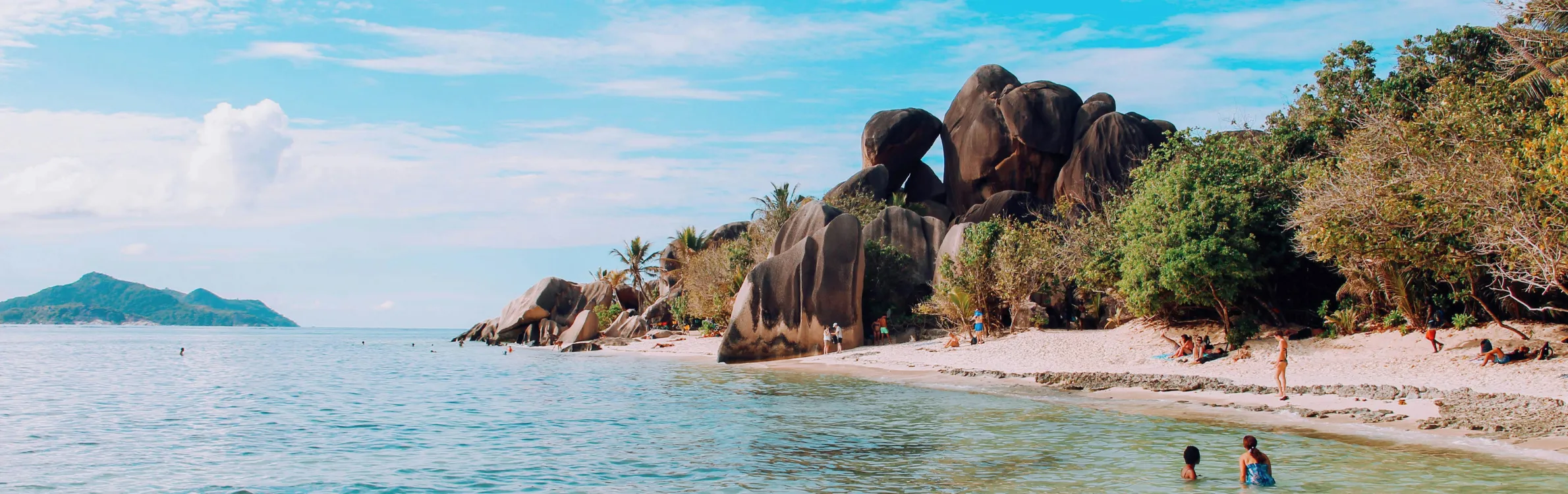 Strand auf Seychellen mit wenig Menschen und großen Steinen im Hintergrund