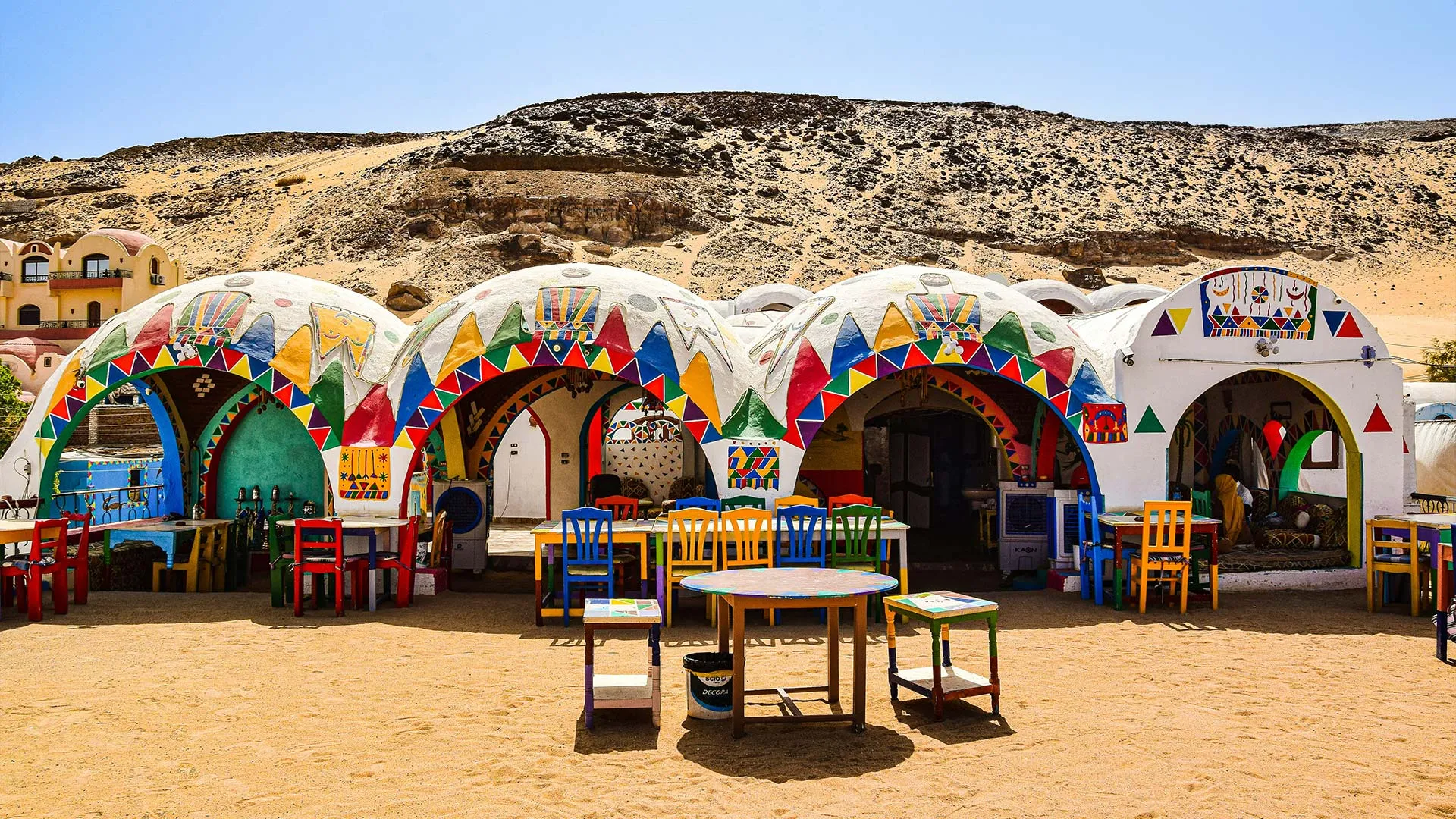 Nubian Village - Bunte Häuser, bemalt mit Kamelen, Pyramiden, Palmen und abstrakten Symbolen