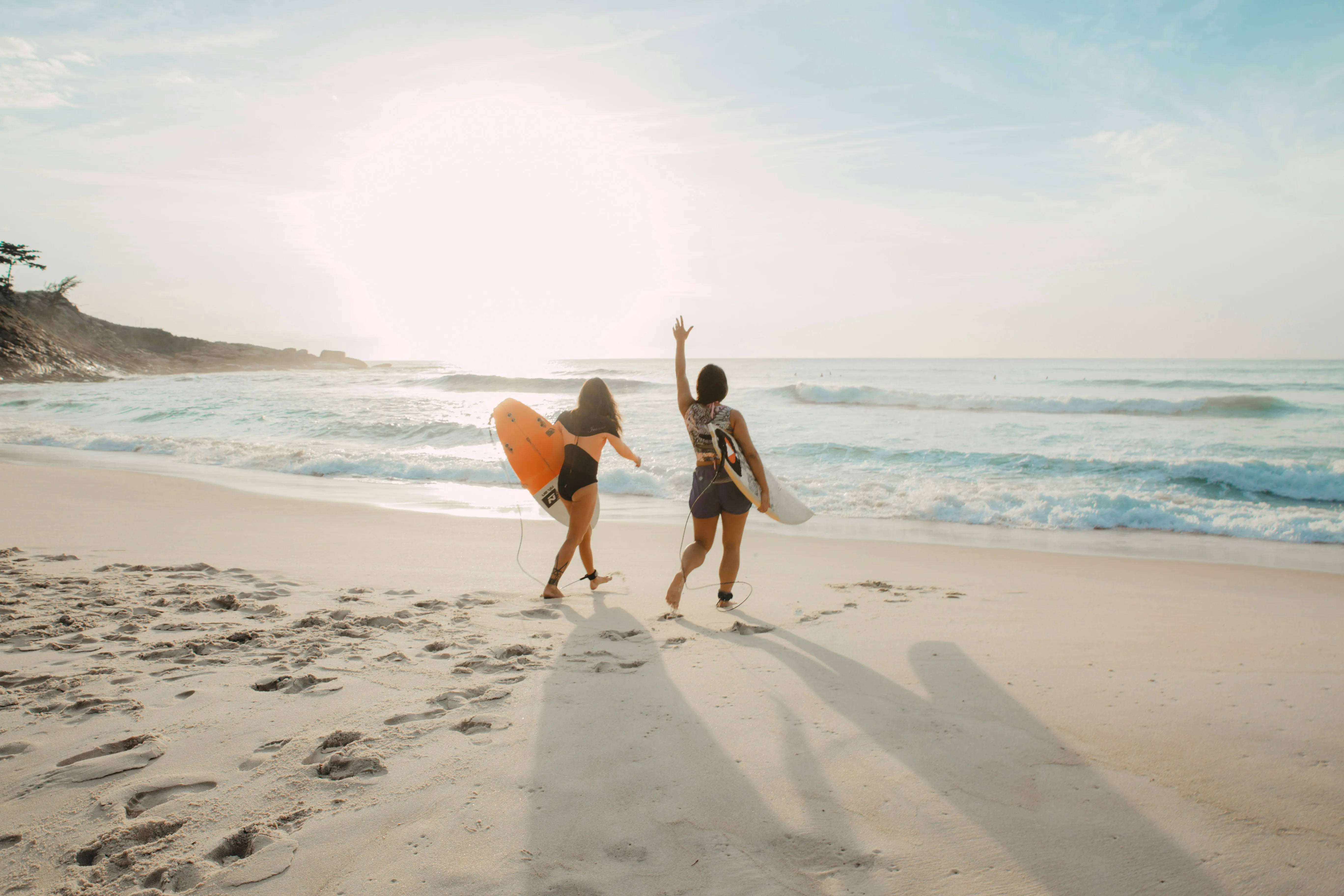 Zwei Menschen mit Surfboards an einem weißen Sandstrand