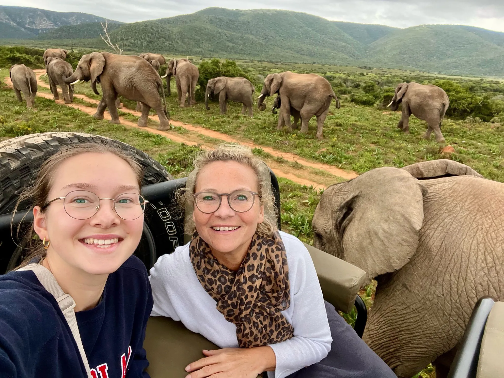 Mutter und Tochter auf einer Safari mit Elefanten im Hintergrund