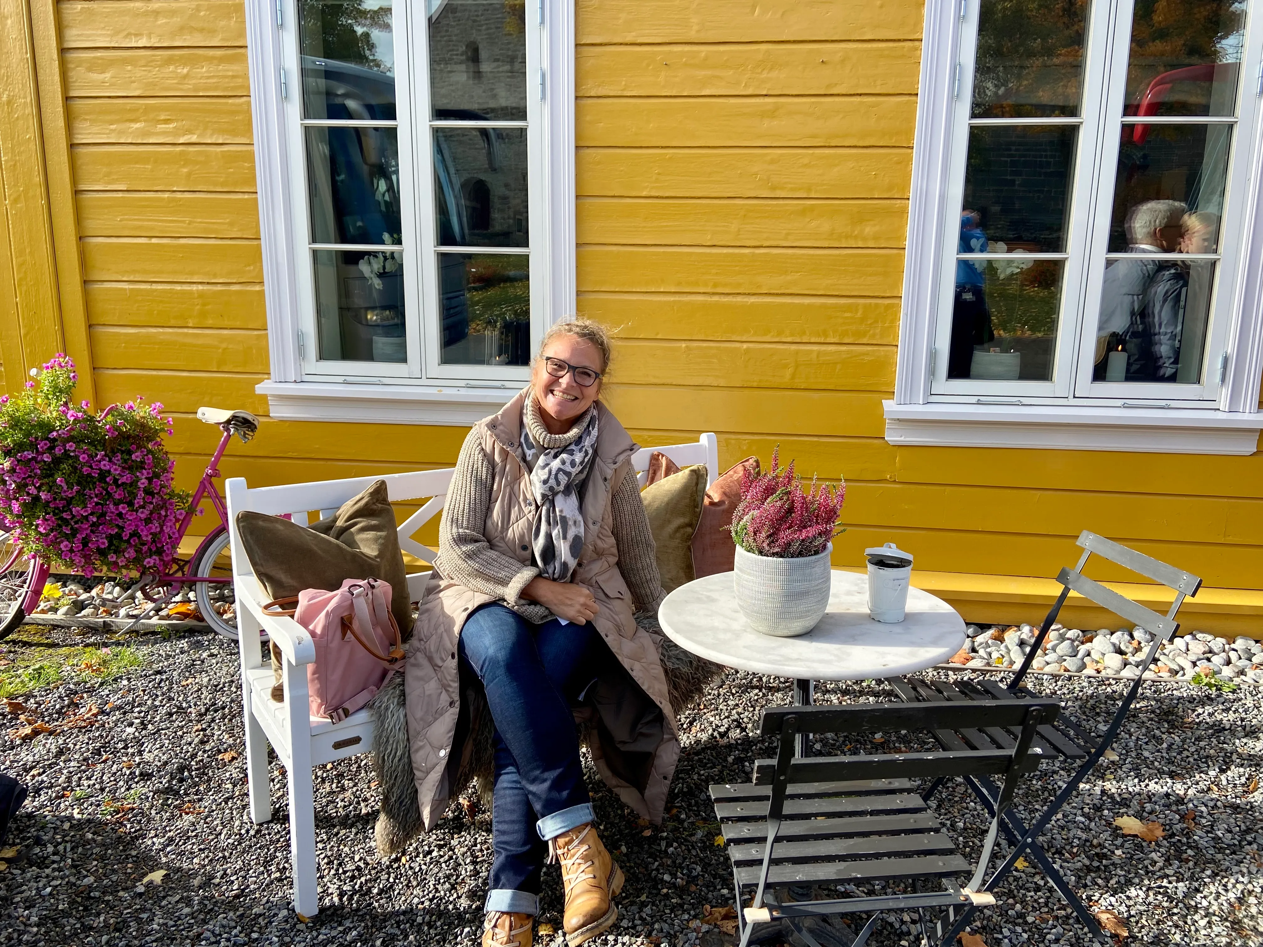 Bettina Zwickler sitzt vor einem gelben Haus in Norwegen