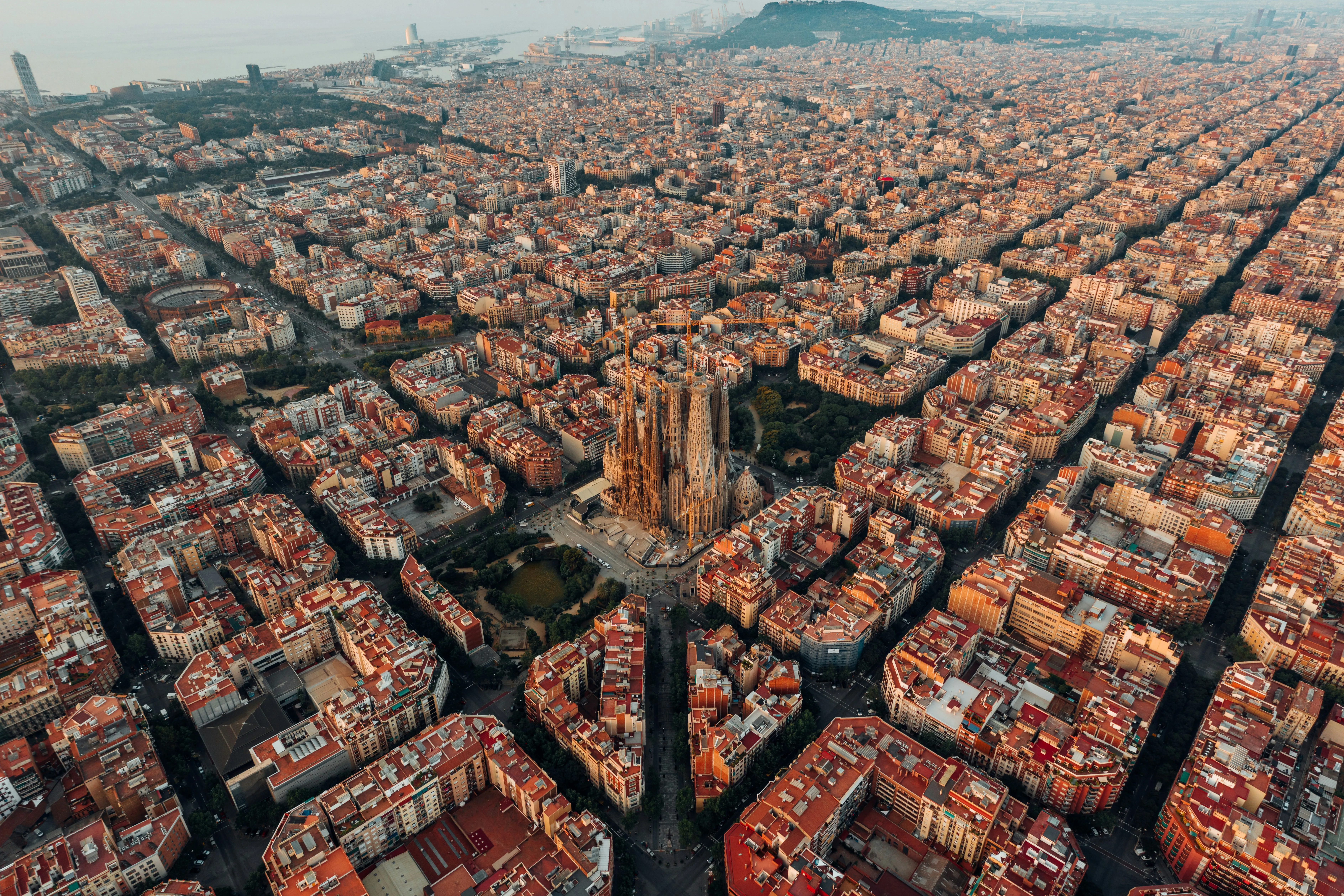 Luftaufnahme der Sagrada Família und des umliegenden, regelmäßig angelegten Stadtviertels mit quadratischen Häuserblöcken in Barcelona.