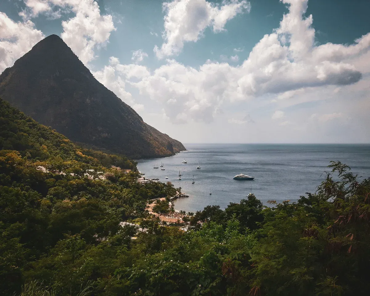 Bucht mit mehreren Segelbooten und einem großen Berg im Hintergrund unter bewölktem Himmel