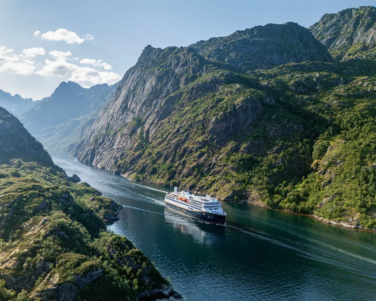 Zwei Personen sitzen in einem Whirlpool auf einem Schiff mit Blick auf einen Fluss und bewaldete Berge