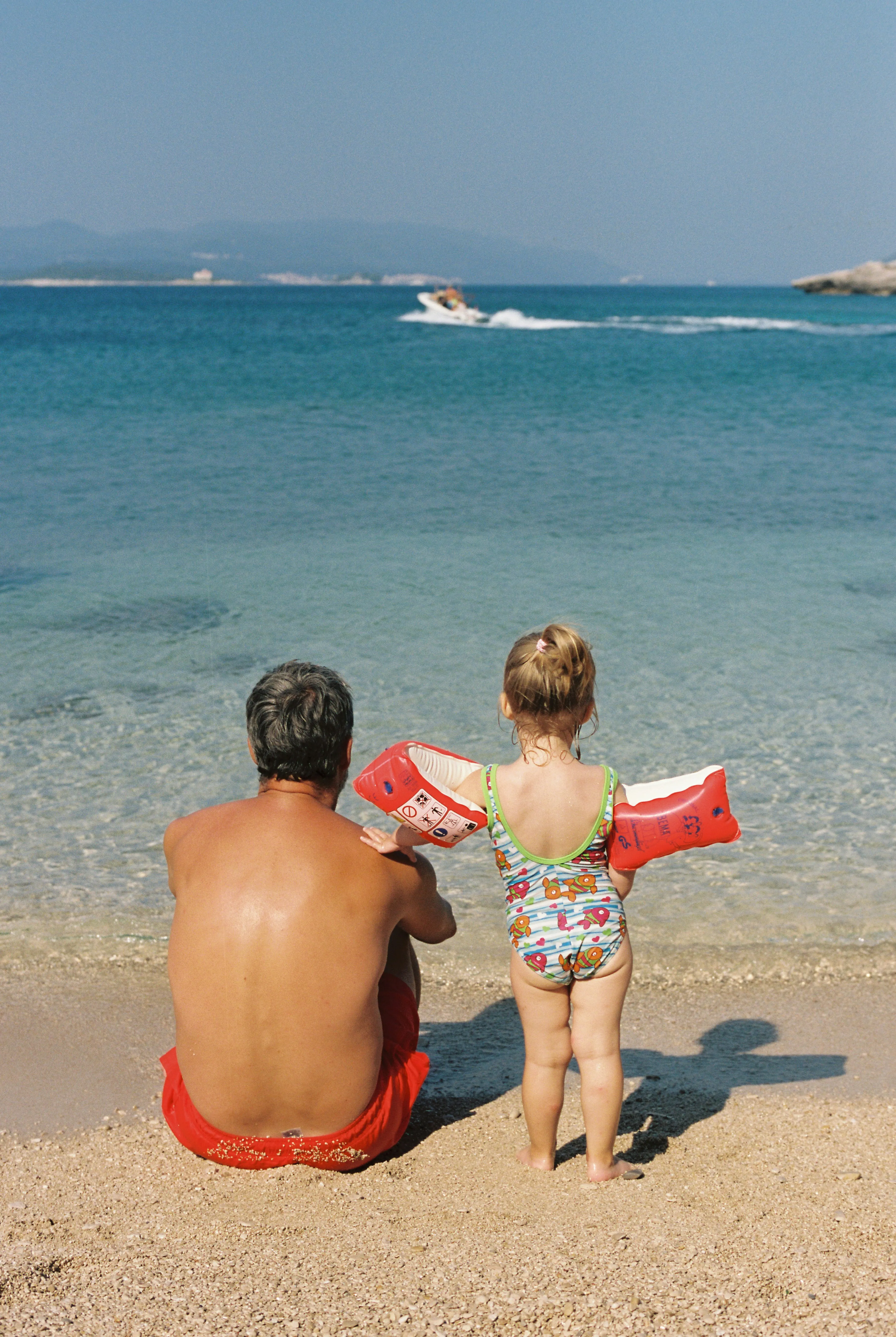 Vater und Tochter stehen in Badekleidung am Meer